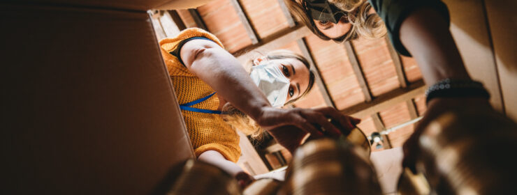 Volunteers are preparing a donation box with nonperishable food - View from inside the cardboard box