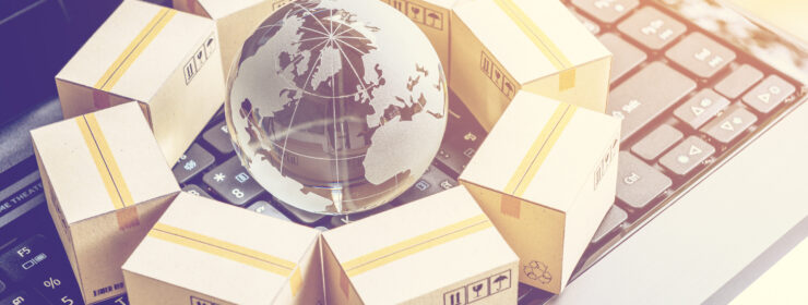 International freight or shipping service for online shopping or ecommerce concept : Paper boxes or carton put in circle around a clear crystal globe with world map on a computer notebook keyboard.