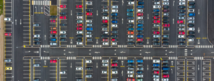 Big modern carpark with symmetrical roads rows of colourful parking bays lots of symmetry and colours aerial view from drone up above looking down