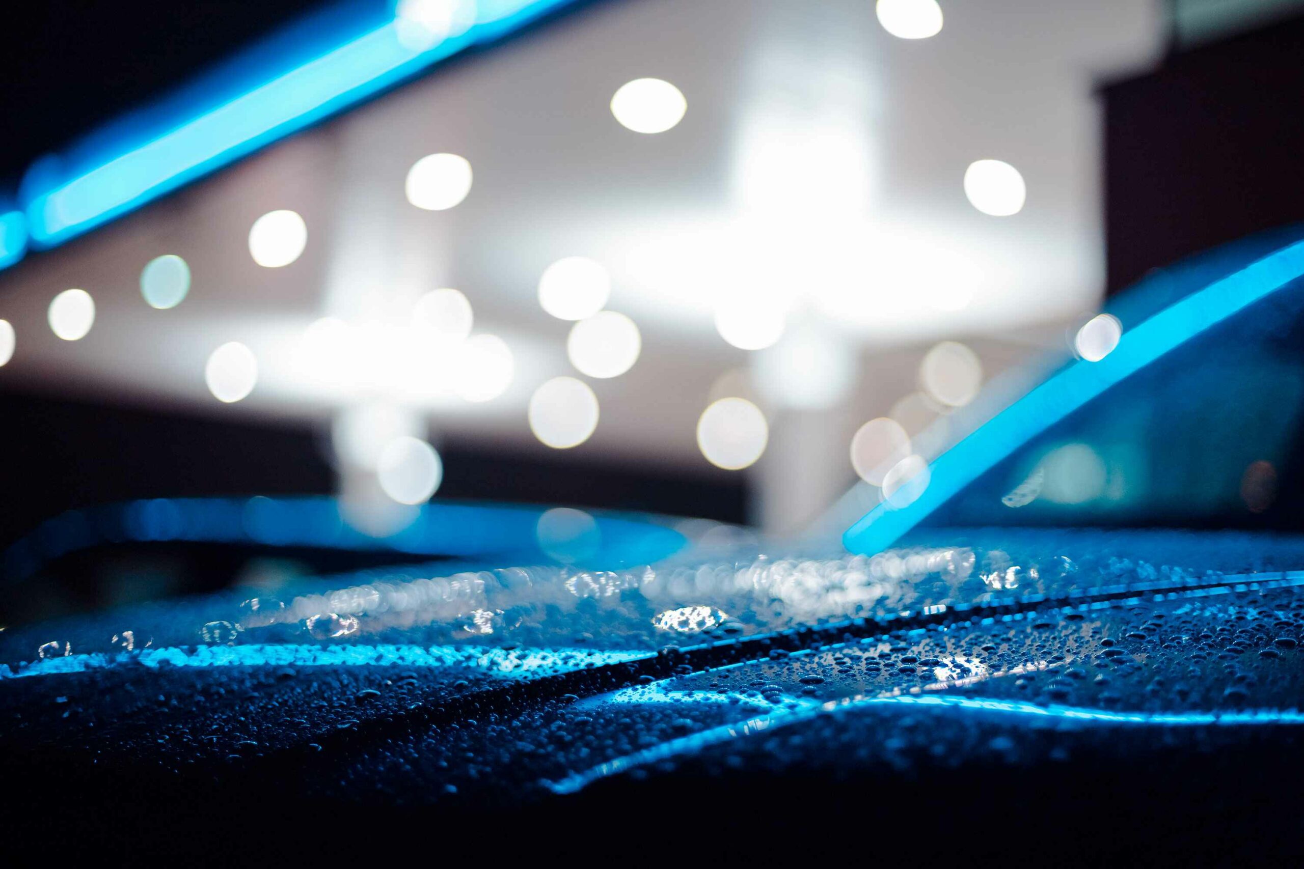 Close-up of a wet car at a petrol station during night