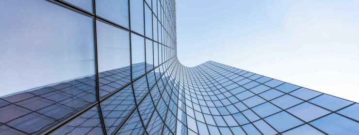 Blue curved glass skyscraper facade against sky