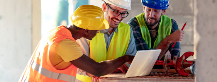 Smiling construction workers viewing laptop