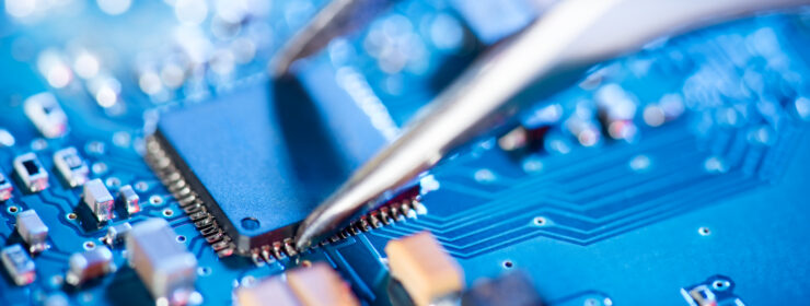 Electronic technician holding tweezers and assembling a circuit board.