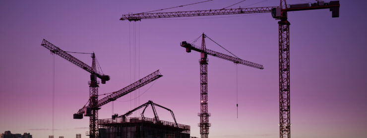 tower cranes around construction site at dusk