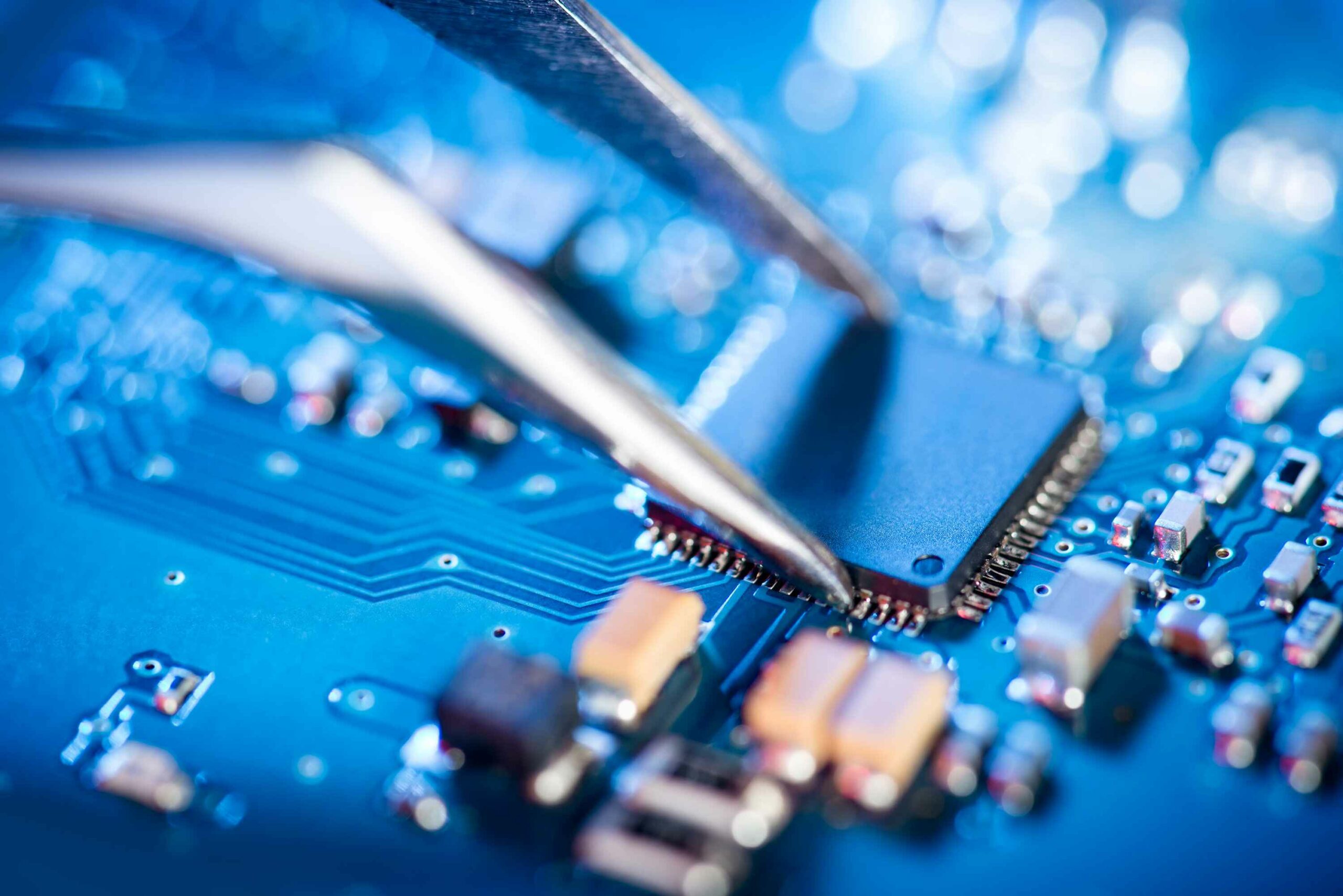 Electronic technician holding tweezers and assemblin a circuit board.