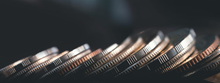 Close up of row of coins on dark background