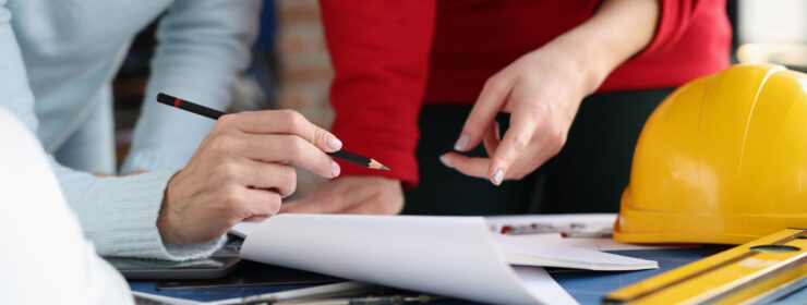 Two women looking at documents and showing them in pencil in design studio